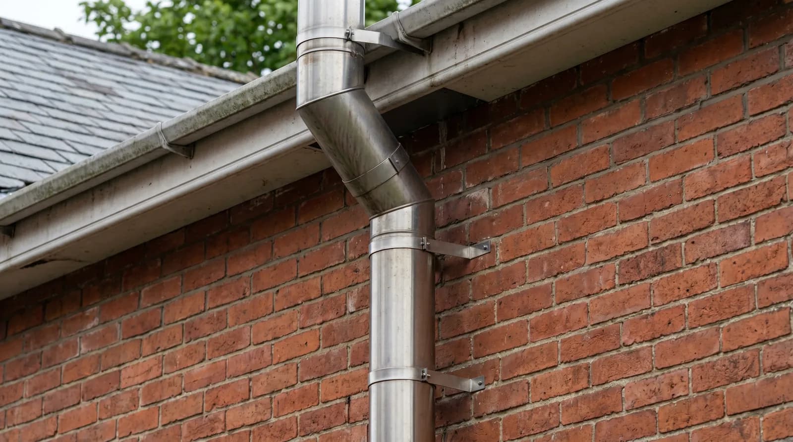 A stainless-steel flue fitted to the outside of a brick house
